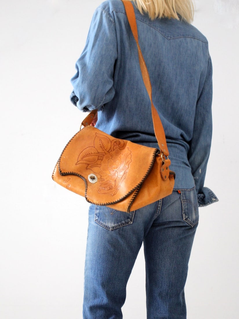 Vintage 70s Tooled Leather Satchel Floral Motif Gold Tone Accents: Vintage 70s Tooled Leather Satchel Floral Motif Gold Tone Accents Explore timeless style with this Vintage 70s Tooled Leather Satchel, expertly crafted from buttery soft tan leather featuring an intri