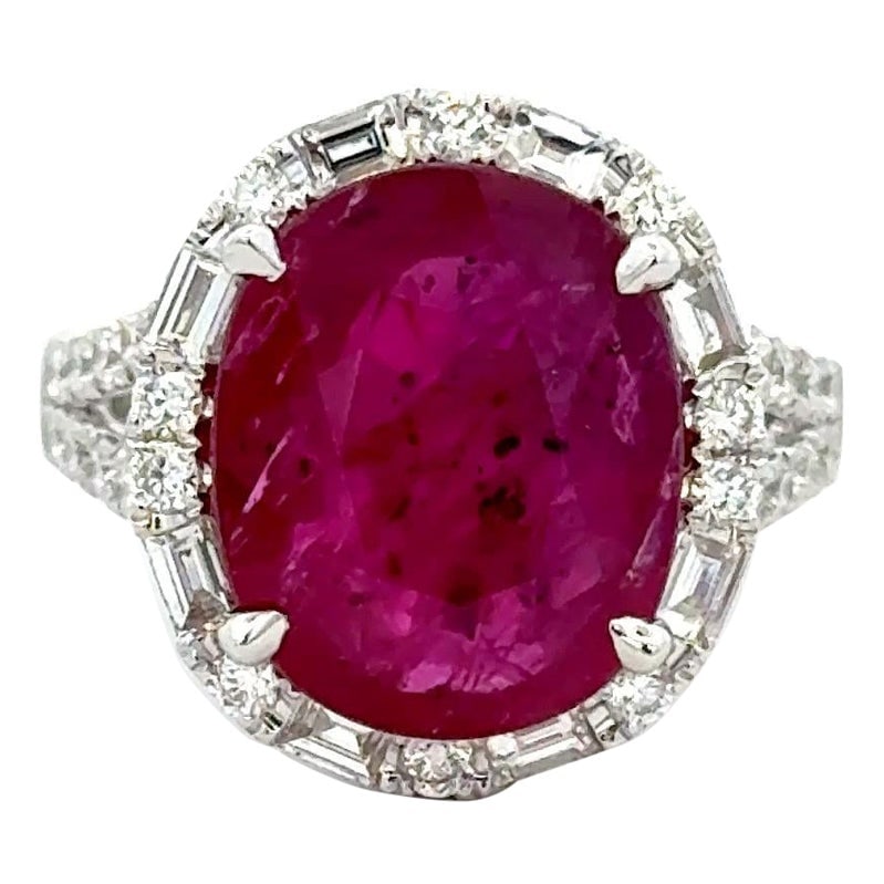 18K White Gold Halo Ring with 7.32ct Oval Ruby and Diamond Accents: 18K White Gold Halo Ring with 7.32ct Oval Ruby and Diamond Accents This elegant cocktail ring is crafted from 18K white gold and features a striking 7.32-carat oval-cut natural ruby with rich red satu