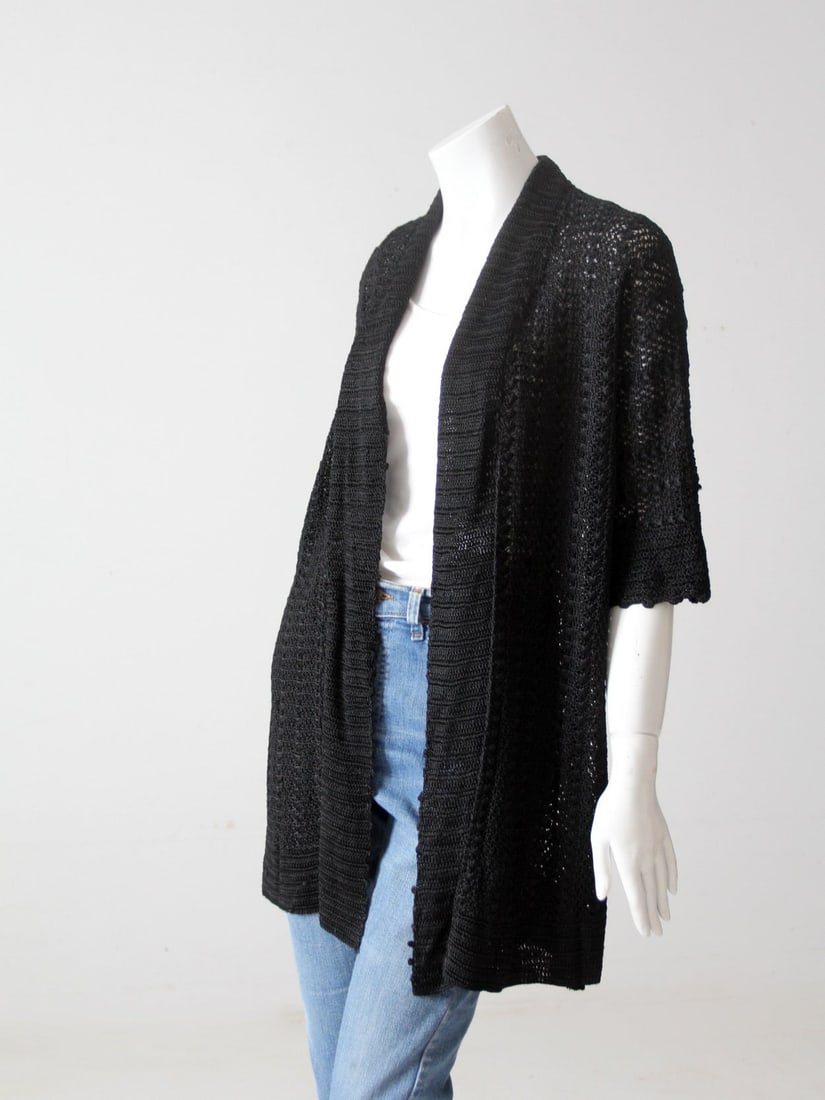 Vintage Black Crochet Cardigan 1980s Chic Slinky Design: Vintage Black Crochet Cardigan 1980s Chic Slinky Design Discover this exquisite vintage black crochet cardigan from the early 1980s, designed for a stylish and timeless look. This slinky long top feat