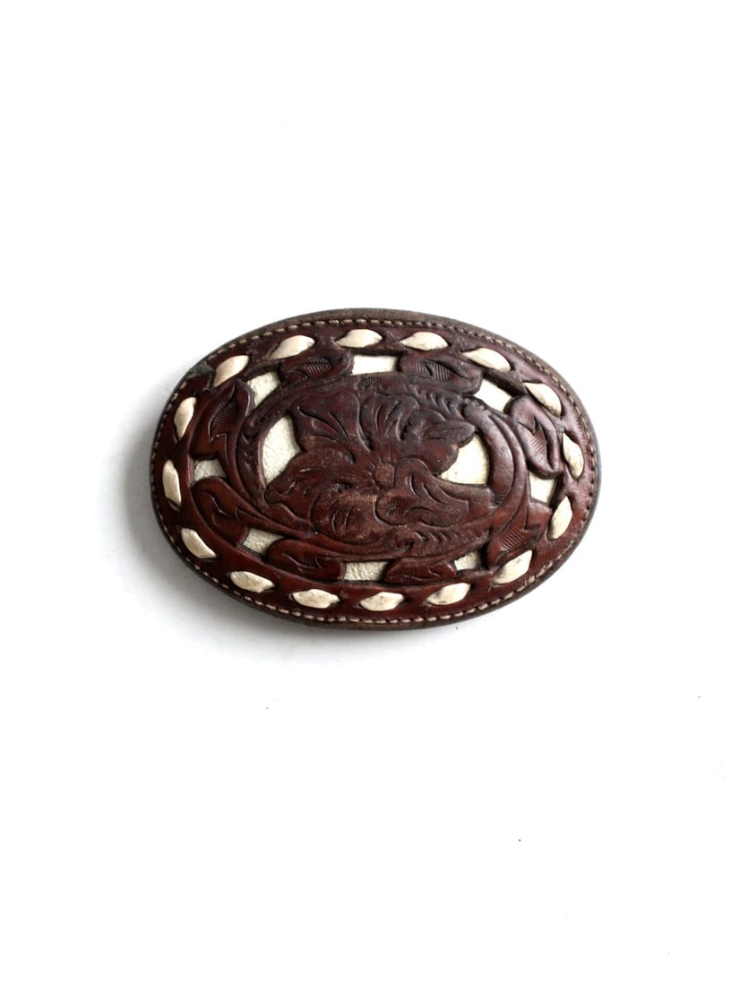 Vintage Motley Hand Tooled Leather Buckle with Floral Design: Vintage Motley Hand Tooled Leather Buckle with Floral Design This vintage tooled leather belt buckle showcases a stunning dark brown finish adorned with an intricate floral pattern. It features a whit