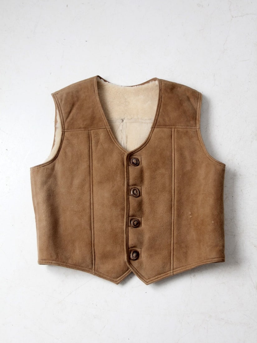 Unisex Vintage Suede Vest with Sherling Lining and Wood Buttons: Unisex Vintage Suede Vest with Sherling Lining and Wood Buttons Experience timeless style with this vintage suede vest featuring a cozy sherling lining. Designed for unisex wear, it showcases elegant 