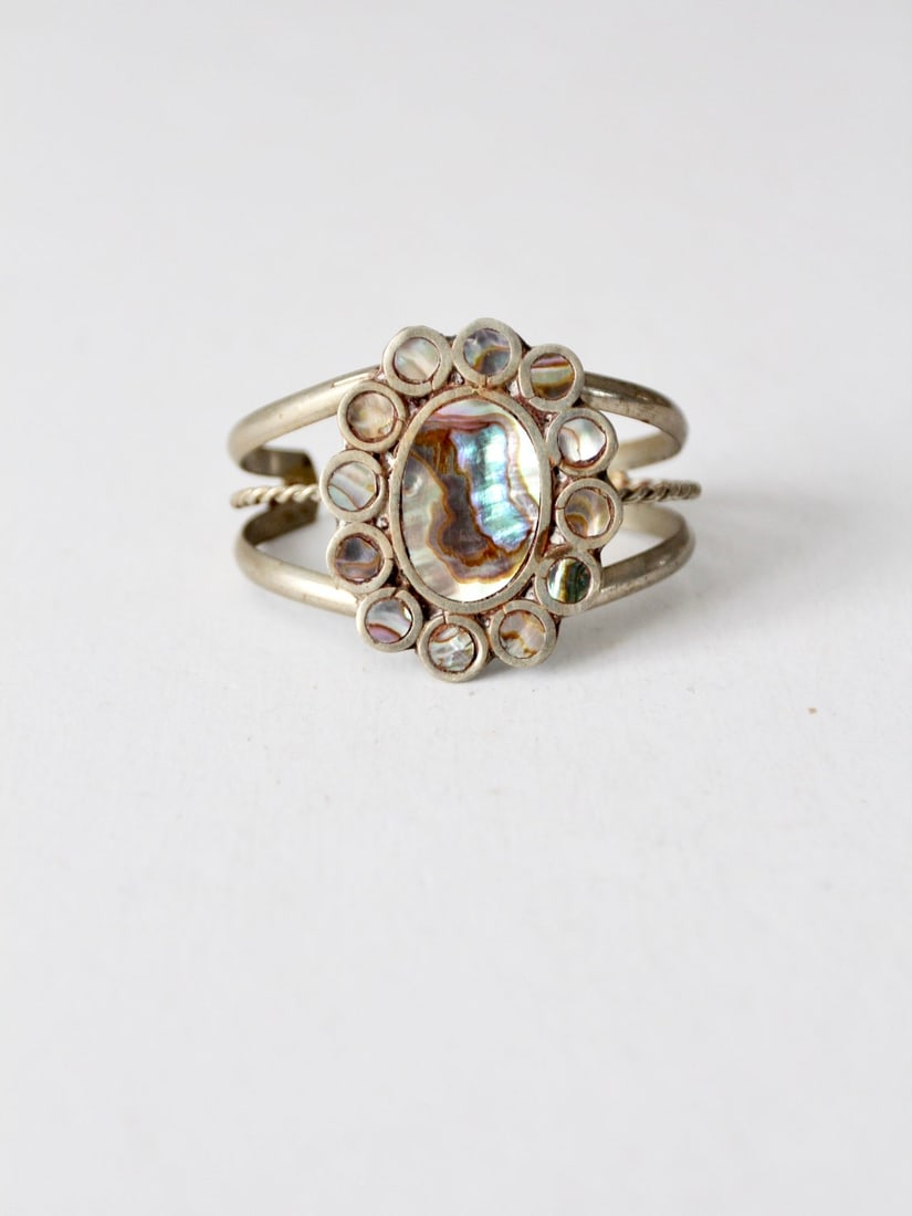Vintage Abalone Shell Cuff Bracelet with Silver Tone Accent: Vintage Abalone Shell Cuff Bracelet with Silver Tone Accent This vintage cuff bracelet showcases a stunning design featuring inlaid abalone shell that shimmers beautifully. The cuff is accented with s