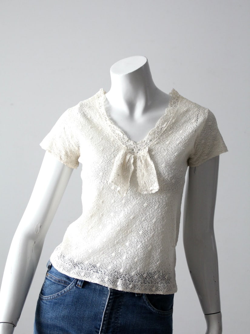Charming Vintage White Lace Blouse with Bow Detail: Charming Vintage White Lace Blouse with Bow Detail This vintage white lace blouse is a charming addition to any wardrobe. Crafted with a delicate lace design, it features a bow detailed v-neck and sof