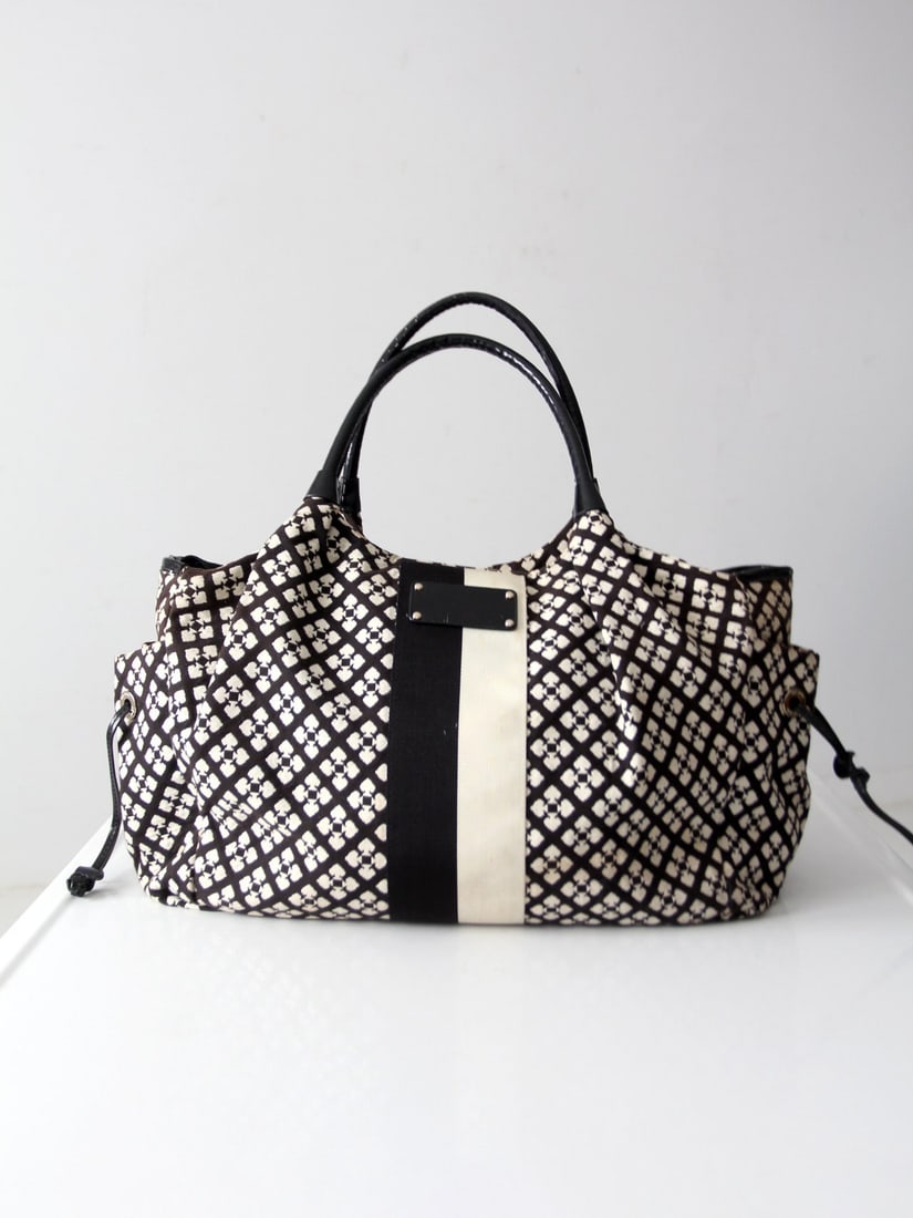 Kate Spade Noel Stevie Bag Black Ivory Geometric Logo Print: Kate Spade Noel Stevie Bag Black Ivory Geometric Logo Print The Kate Spade Noel Stevie Bag showcases a stylish black and ivory geometric logo print with a contrasting cream center stripe. Crafted from