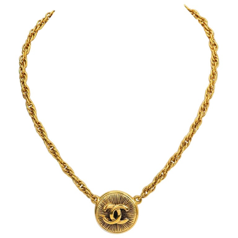 1980s Chanel Sunburst Pendant Choker Necklace with CC Logo Gold Plate: 1980s Chanel Sunburst Pendant Choker Necklace with CC Logo Gold Plate This Chanel choker from the 1980s features a 'CC' sunburst pendant with gold plate construction and gold-tone hardware. The neckla