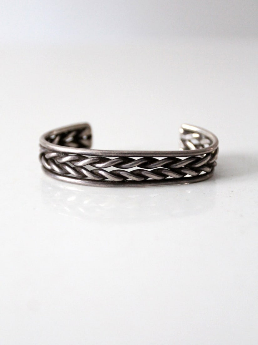 Vintage Silver Tone Braided Metal Cuff Bracelet: Vintage Silver Tone Braided Metal Cuff Bracelet Discover the charm of this vintage braided metal cuff, showcasing a striking thick silver tone design with a twisted braid at its center. This cuff is i