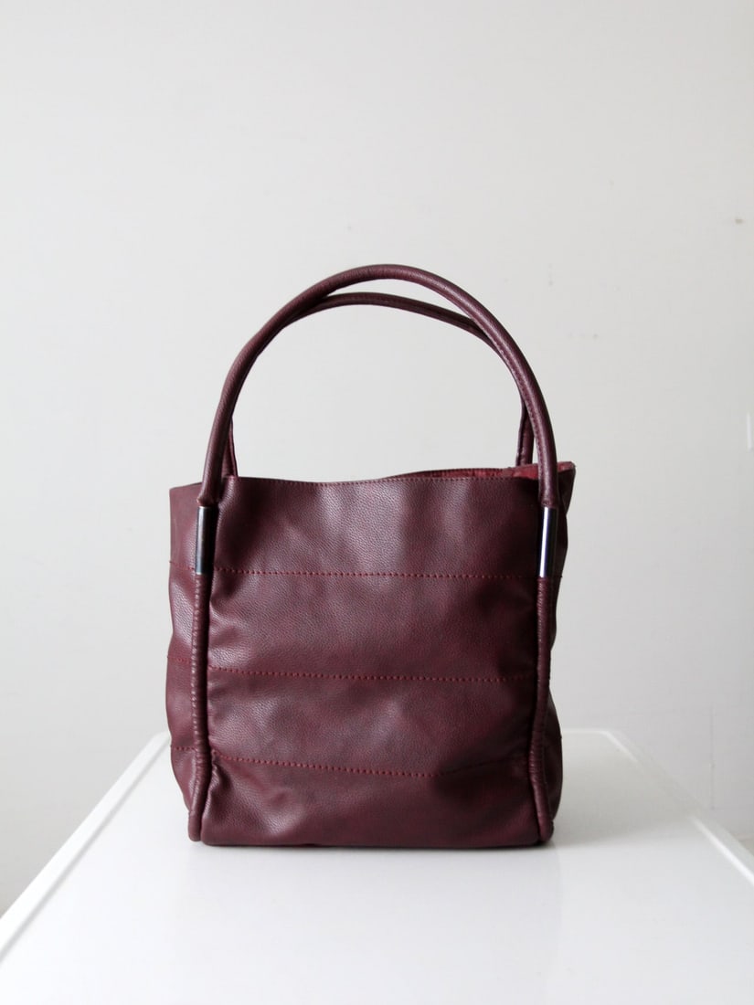 Burgundy Leather Shoulder Tote by Neiman Marcus from the 1990s: Burgundy Leather Shoulder Tote by Neiman Marcus from the 1990s This 1990s shoulder bag is crafted from deep burgundy pebbled leather and features a softly structured silhouette. It is designed with ro