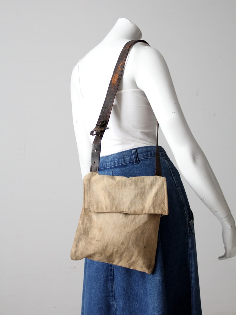 Beige Vintage Textile Leather Messenger Bag with Grommets: Beige Vintage Textile Leather Messenger Bag with Grommets This vintage messenger bag combines a unique textile design with a durable leather strap, making it a stylish yet practical accessory. The bei
