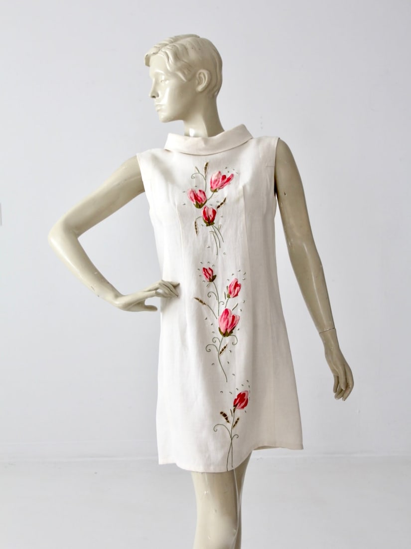Charming Vintage Linen Shift Dress with Pink Floral applique: Charming Vintage Linen Shift Dress with Pink Floral applique This charming vintage linen shift dress showcases a delightful mod aesthetic with pops of pink florals adorning the fabric. The white linen