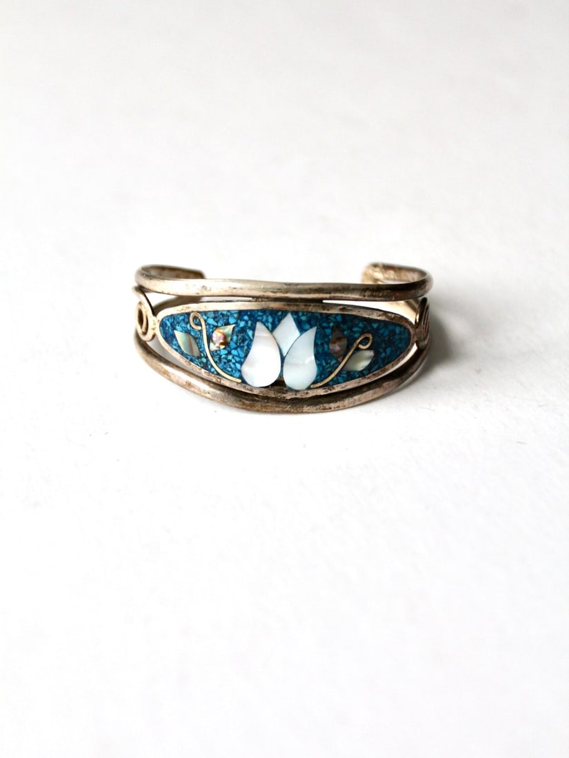 Vintage Mexican Abalone Shell and Alpaca Silver Cuff Bracelet: Vintage Mexican Abalone Shell and Alpaca Silver Cuff Bracelet This vintage Mexican cuff bracelet showcases the stunning beauty of abalone shell inlay complemented by a sleek alpaca silver base. The in