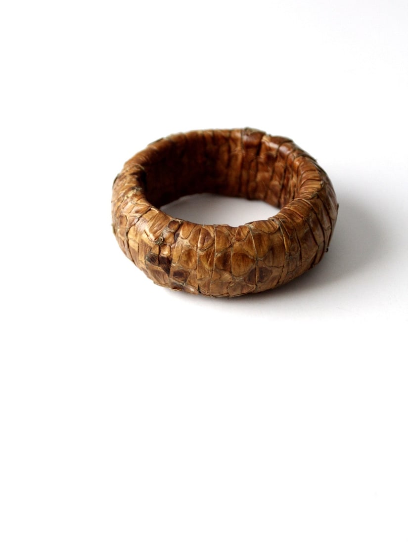 Chunky Vintage Snakeskin Bangle Bracelet in Golden Brown: Chunky Vintage Snakeskin Bangle Bracelet in Golden Brown This vintage snakeskin bangle bracelet features a chunky design adorned with a golden brown snakeskin overlay in a ribbed pattern. It is in goo
