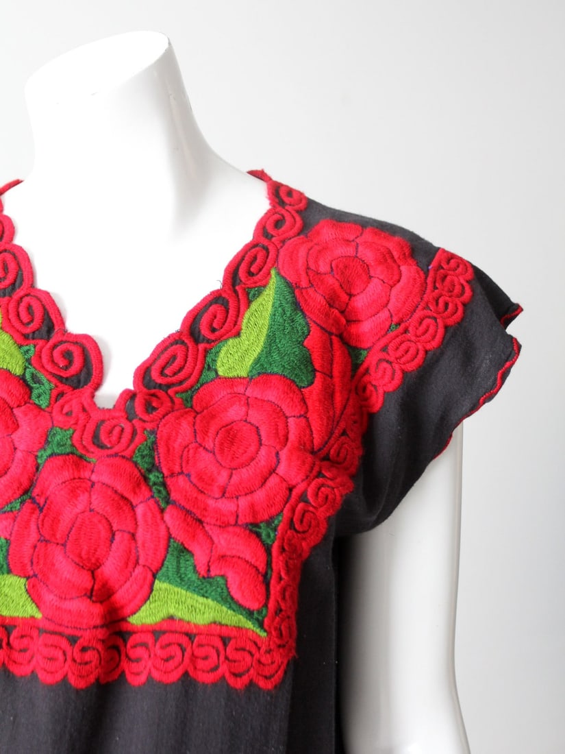 Vintage 70s Huipil Blouse Black Cotton Floral Embroidery: Vintage 70s Huipil Blouse Black Cotton Floral Embroidery Embrace vintage charm with this stunning 70s floral huipil style blouse. Crafted from soft black cotton, this blouse features exquisite red and