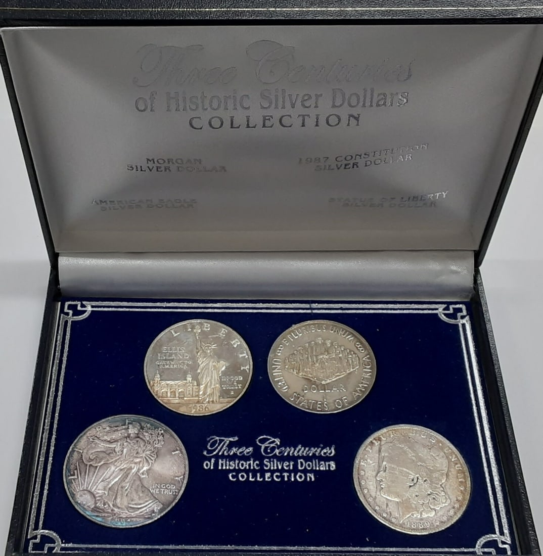 Four Historic US Silver Dollar Coins Morgan Commemoratives ASE in Display Case: Four Historic US Silver Dollar Coins Morgan Commemoratives ASE in Display Case This set features four historic United States silver dollars spanning three centuries. Included are a 19th century Morgan