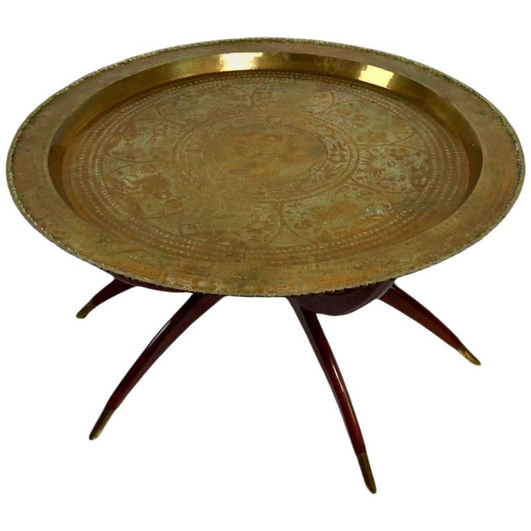 Vintage Moroccan Brass Tray Top Table with Mahogany Spider Legs: Vintage Moroccan Brass Tray Top Table with Mahogany Spider Legs This captivating brass tray top table features a unique folding mahogany spider leg base, making it both functional and stylish. Likely 