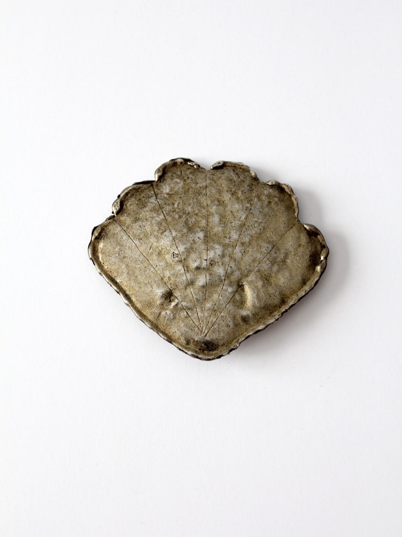 Vintage Silver Tone Shell Shaped Slide Back Belt Buckle: Vintage Silver Tone Shell Shaped Slide Back Belt Buckle This vintage shell-shaped belt buckle showcases a charming fan design with a rippled edge and a lovely patina in its silver tone. Ideal for addi