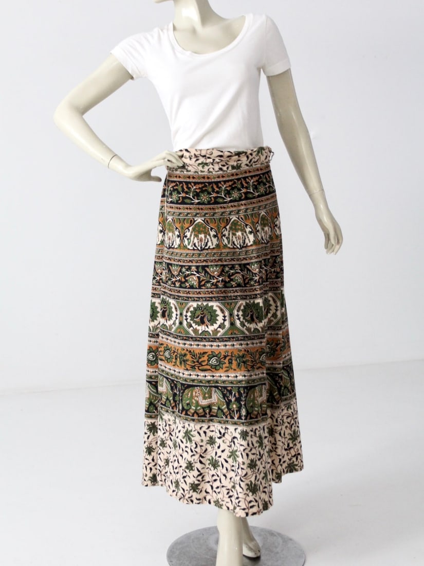 1970s Vintage Wrap Skirt with Elephants and Giraffes: 1970s Vintage Wrap Skirt with Elephants and Giraffes This stunning vintage 1970s wrap skirt is adorned with vibrant block prints featuring elephants, giraffes, and birds. Made from 100% cream cotton,