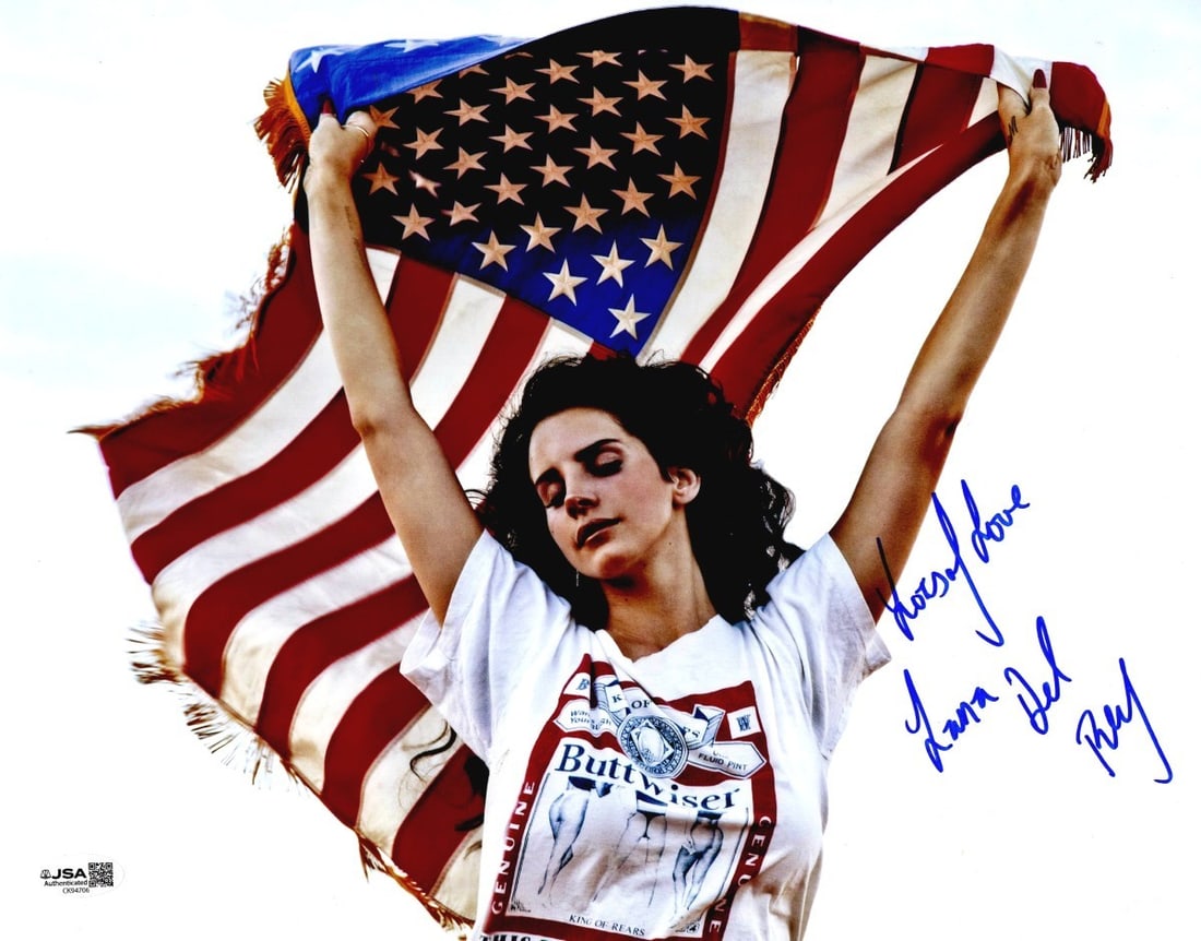 Lana Del Rey signed 11x14 photograph JSA authenticated: Lana Del Rey signed 11x14 photograph JSA authenticated This is an original 11x14 photograph of Lana Del Rey holding an American flag, personally signed by Lana Del Rey. The autograph has been authenti