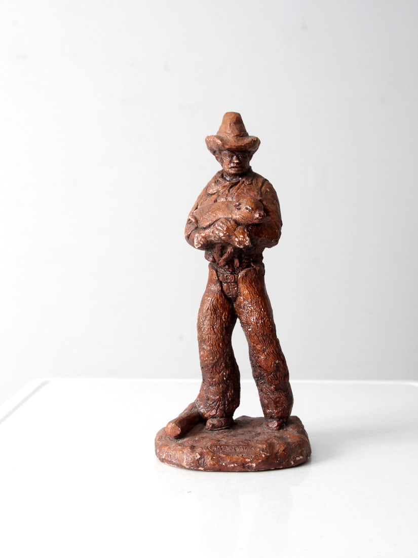 Vintage Cowboy Statue Maverick Faux Bois 13.75 Inch: Vintage Cowboy Statue Maverick Faux Bois 13.75 Inch This vintage Western cowboy statue captures the essence of cowboy culture, depicting a cowboy holding a piglet. The statue features a plaster faux b