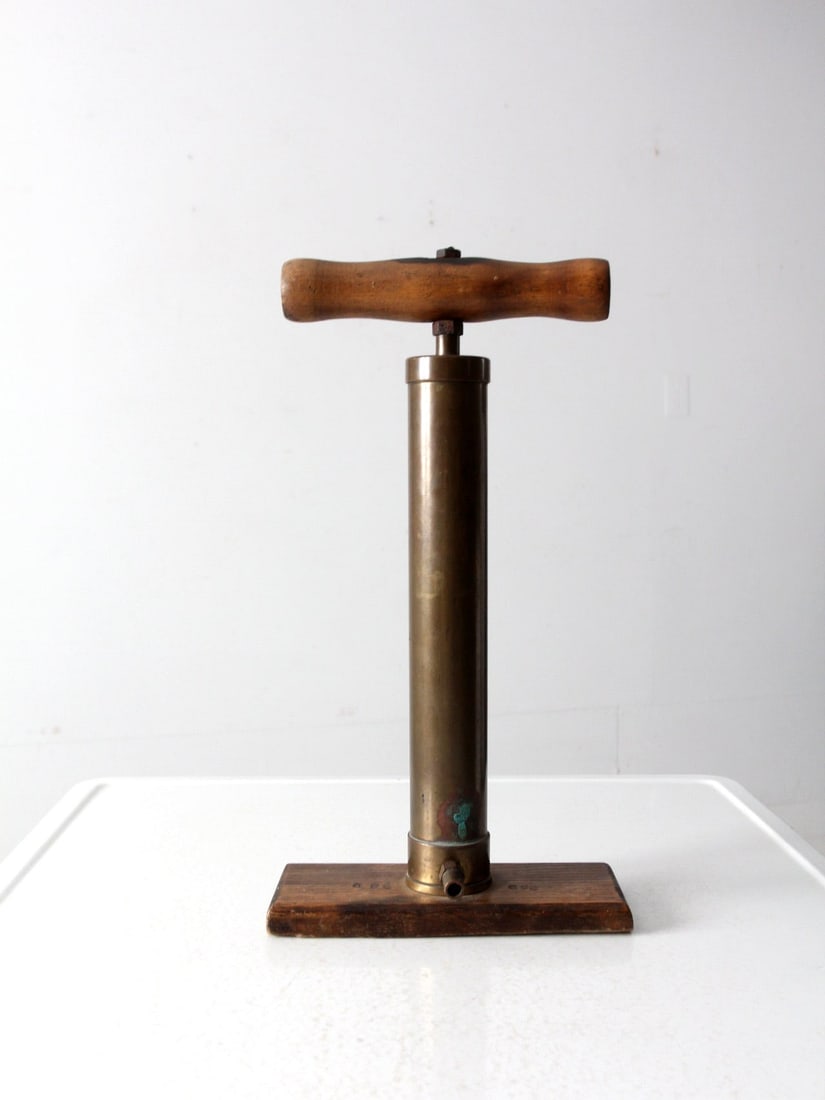 Antique Brass Bicycle Pump 1920s Wooden Handle Vintage Decor: Antique Brass Bicycle Pump 1920s Wooden Handle Vintage Decor This vintage brass bicycle pump, dating back to the 1920s-1930s, showcases a classic design with a wooden handle and a sturdy wooden base. 