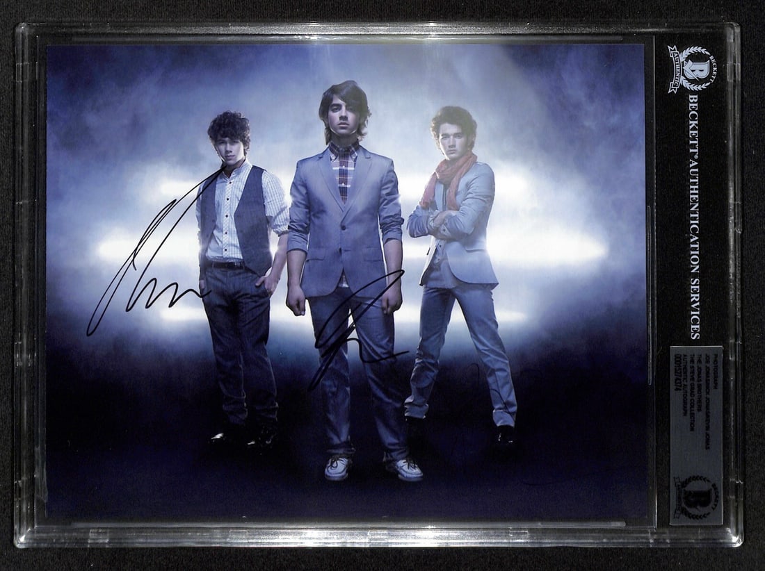 Jonas Brothers Signed 8x10 Photo with Beckett Authentication: Jonas Brothers Signed 8x10 Photo with Beckett Authentication This vibrant 8x10 color photograph features the iconic Jonas Brothers--Nick Jonas, Joe Jonas, and Kevin Jonas--each signing in bold black p