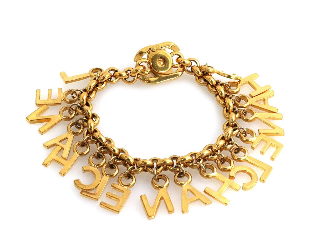 Chanel vintage gold-plated charm bracelet with turnlock letters: Chanel vintage gold-plated charm bracelet with turnlock letters This authentic vintage Chanel charm bracelet features substantial sculptural links in gold-plated metal, adorned with playful multi-lett