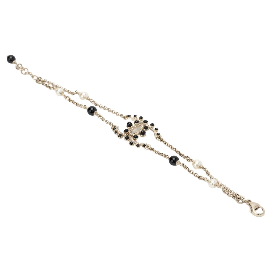 Chanel V 19 Champagne Gold Bracelet with Black Gripoix and Rhinestones: Chanel V 19 Champagne Gold Bracelet with Black Gripoix and Rhinestones This exquisite Chanel bracelet is a stunning addition to any jewelry collection. Crafted in delicate champagne gold, it features 