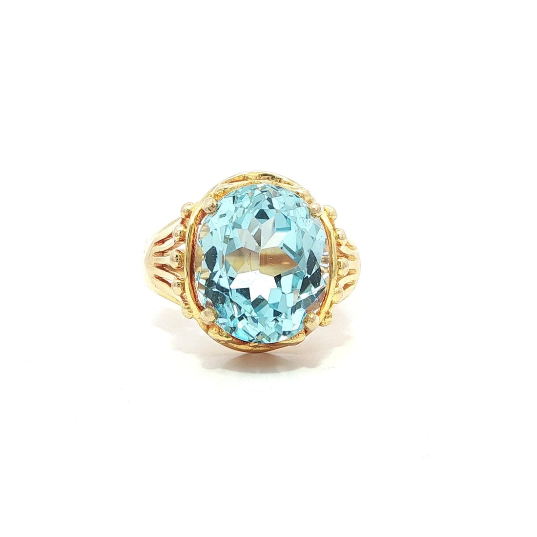 Vintage 14k Yellow Gold Blue Topaz Solitaire Flared Ring: Vintage 14k Yellow Gold Blue Topaz Solitaire Flared Ring This exquisite vintage cocktail ring features a stunning oval blue topaz, showcasing a brilliant cut that captures the light beautifully. The n