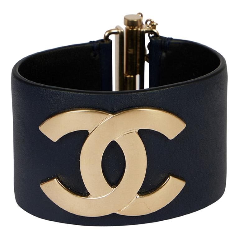 Chanel Navy Leather Cuff Bracelet with Satin Silver CC Logo: Chanel Navy Leather Cuff Bracelet with Satin Silver CC Logo This Chanel navy blue leather cuff bracelet features a stunning satin silver CC center logo, embodying elegance and style. Crafted in France