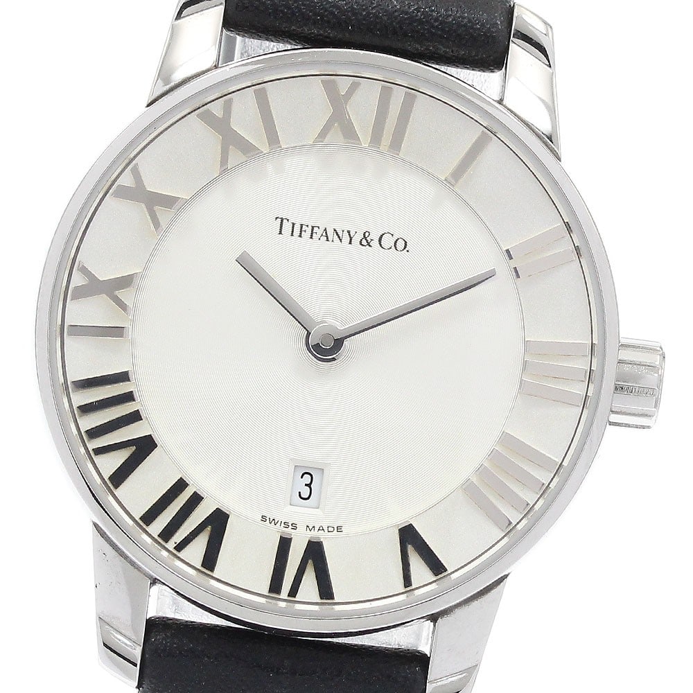 Tiffany Atlas Dome quartz date ladies wristwatch: Tiffany Atlas Dome quartz date ladies wristwatch This Tiffany & Co. Atlas Dome women's wristwatch features a stainless steel case with a silver dial and a leather bracelet. The watch is powered by a q