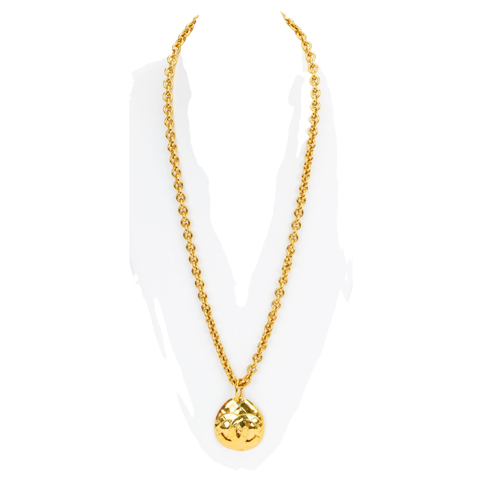 Chanel Spring 1994 Vintage Gold Quilted Pendant Necklace with CC Logo: Chanel Spring 1994 Vintage Gold Quilted Pendant Necklace with CC Logo This Chanel necklace from the Spring 1994 collection features a gold-tone chain and a distinctive egg-shaped quilted pendant adorn