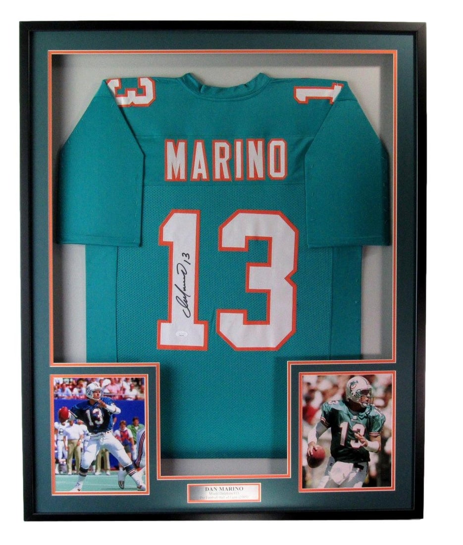 Framed Miami Dolphins Jersey Signed by Dan Marino with Photos JSA Authenticated: Framed Miami Dolphins Jersey Signed by Dan Marino with Photos JSA Authenticated This offering features a Dan Marino Hall of Fame Signed/Autographed Teal Football Jersey framed alongside photos of the 