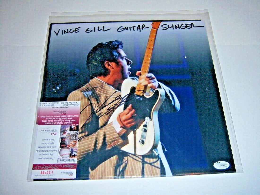Vince Gill Autographed Record Album Photo with JSA Authentication: Vince Gill Autographed Record Album Photo with JSA Authentication This is an original record album featuring Vince Gill, the renowned country music singer. The album, titled "Guitar Slinger," includes
