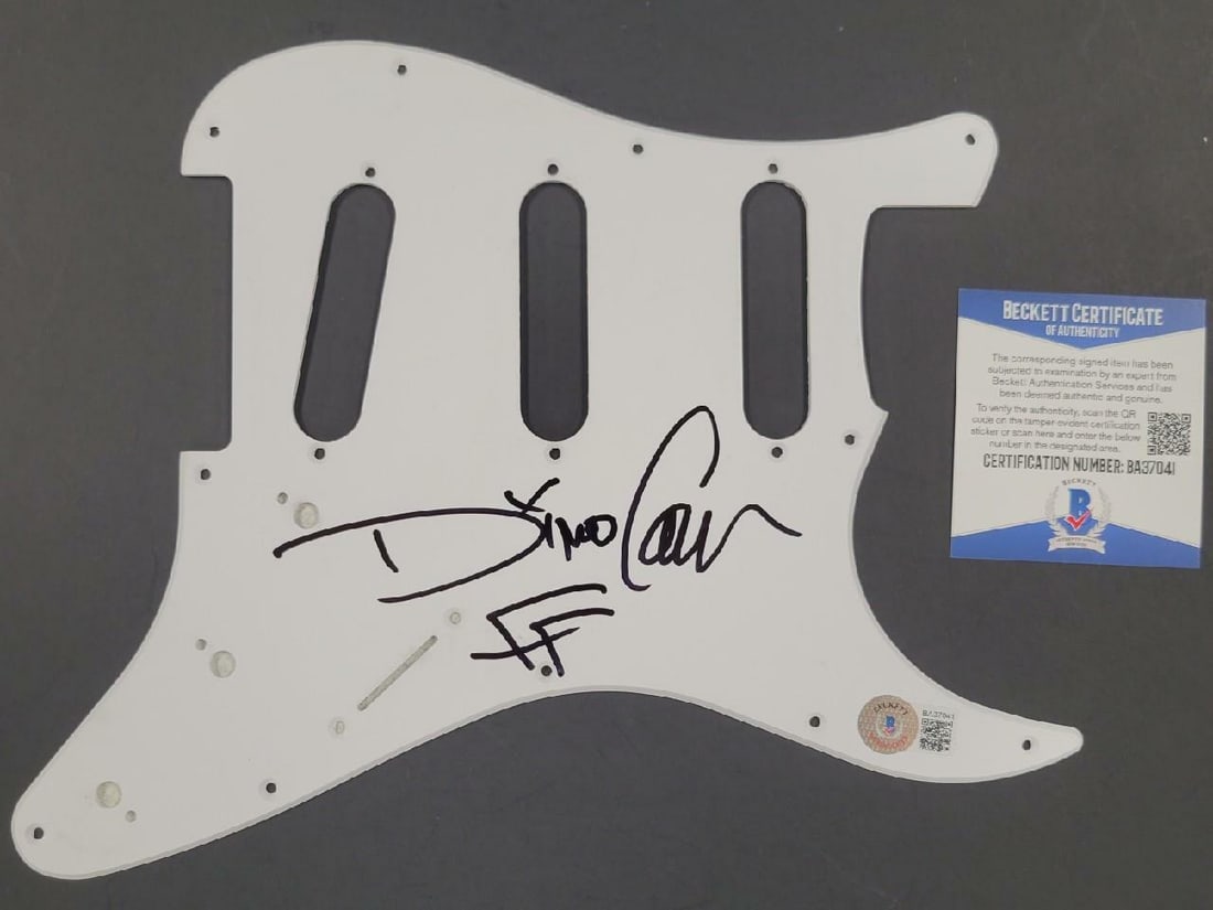 Dino Cazares Autographed White Guitar Pickguard with Beckett Authentication: Dino Cazares Autographed White Guitar Pickguard with Beckett Authentication This is an original white electric guitar pickguard signed by Dino Cazares of Fear Factory. The autograph is authenticated b
