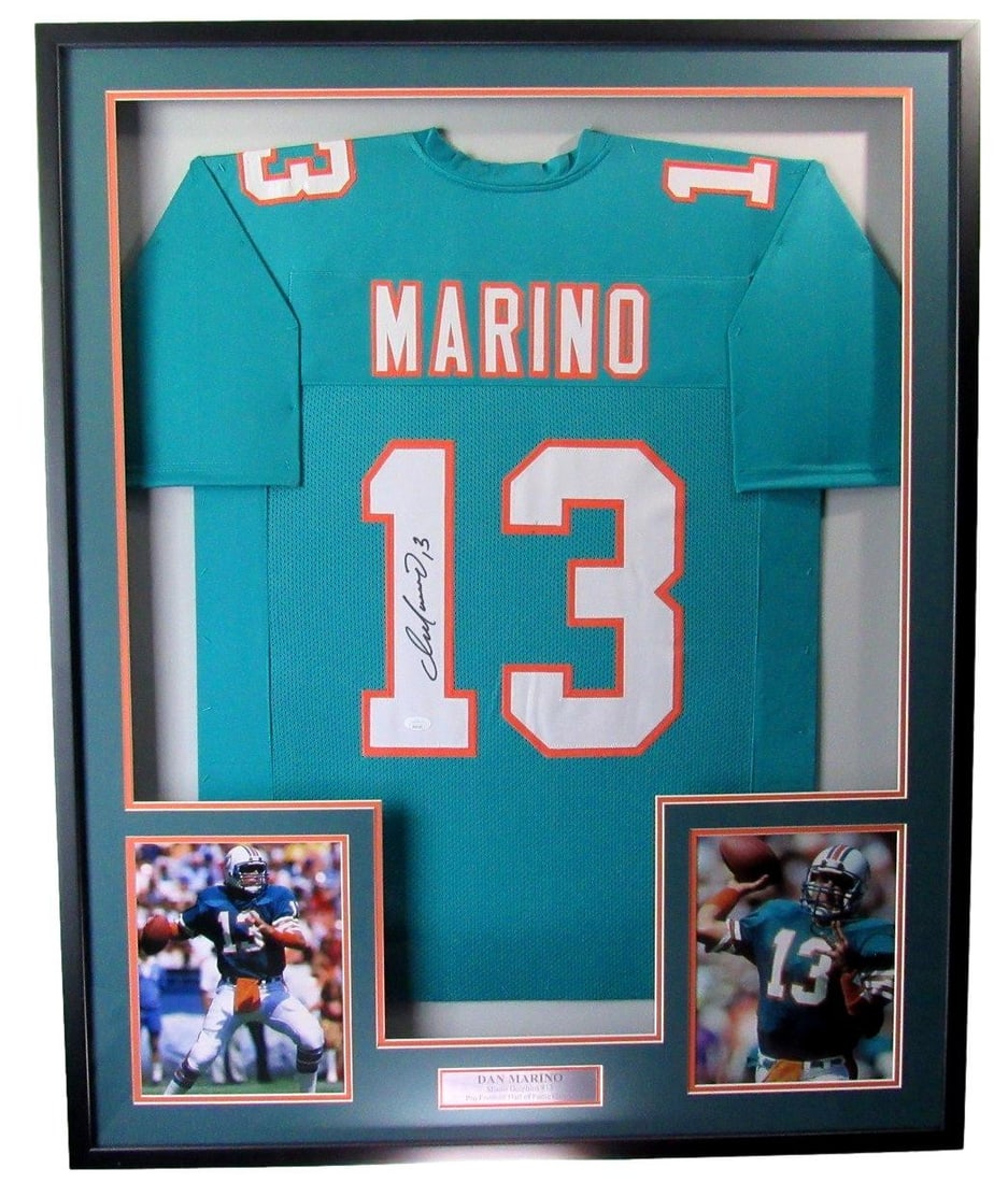 Framed Dan Marino Autographed Dolphins Jersey With Photos JSA Authenticated: Framed Dan Marino Autographed Dolphins Jersey With Photos JSA Authenticated This framed display features a teal Miami Dolphins football jersey autographed by Hall of Famer Dan Marino. The jersey is pr