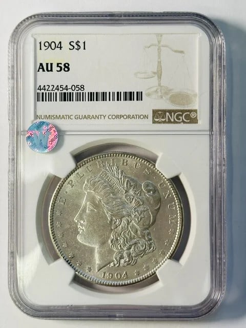 1904 NGC AU-58 Morgan Dollar Silver: 1904 NGC AU-58 Morgan Dollar Silver This 1904 Morgan Silver Dollar is certified by NGC with a grade of AU 58, indicating attractive detail and minimal wear. The coin is composed of silver and originat