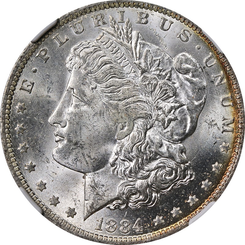 NGC MS63 1884-O Morgan Dollar with Attractive Peripheral Toning: NGC MS63 1884-O Morgan Dollar with Attractive Peripheral Toning This is an 1884-O Morgan Silver Dollar graded MS63 by NGC. The coin features peripheral toning and is composed of silver with a fineness