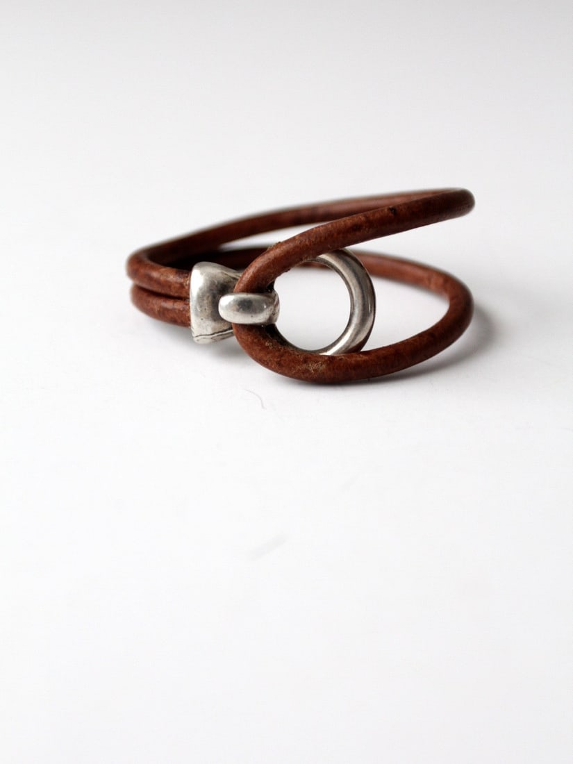 1970s Vintage Leather Bracelet with Silver Tone Clasp: 1970s Vintage Leather Bracelet with Silver Tone Clasp Discover this exquisite 1970s vintage leather bracelet, showcasing beautifully aged tubed brown leather that creates a unique strap design. It fea