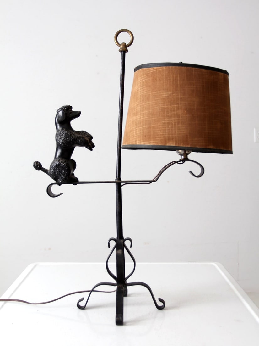 Charming Vintage Wrought Iron Poodle Table Lamp with Tan Shade: Charming Vintage Wrought Iron Poodle Table Lamp with Tan Shade Illuminate your space with this charming vintage wrought iron table lamp featuring a delightful poodle figurine. The lamp showcases an in