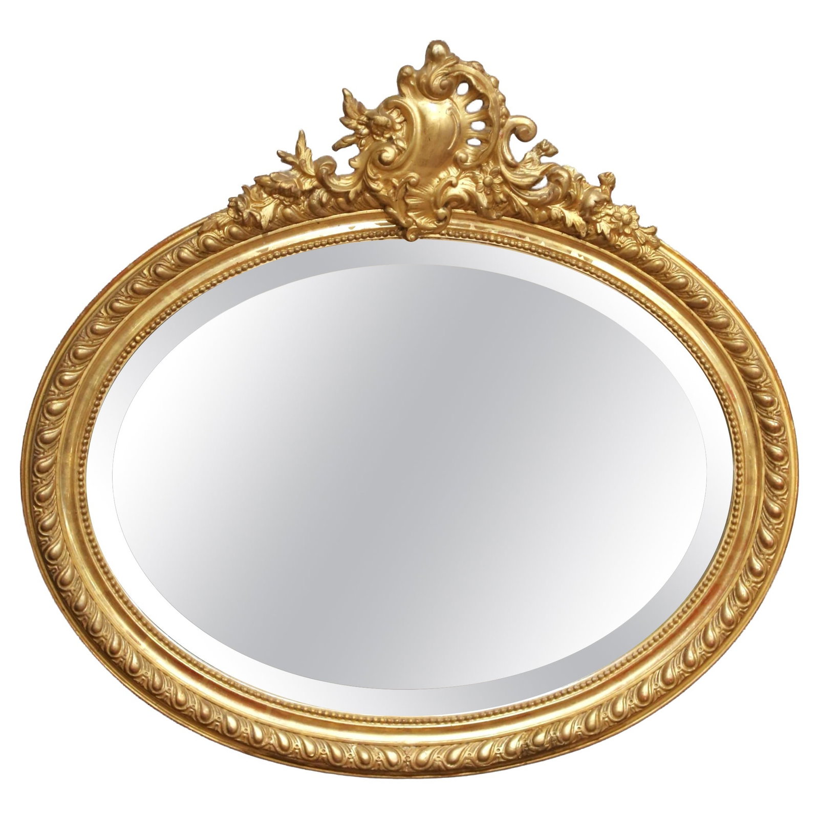 French Louis XV Giltwood Beveled Wall Mirror with Crest: French Louis XV Giltwood Beveled Wall Mirror with Crest This late 19th-century French wall mirror features an oval giltwood frame crafted in the Louis XV style. The frame is richly carved and crowned 