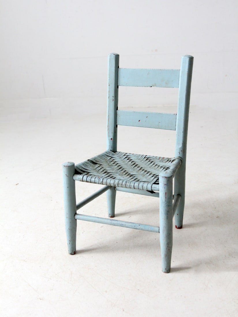 Antique Light Blue Children's Chair with Woven Seat: Antique Light Blue Children's Chair with Woven Seat This charming antique children's chair showcases a rustic ladder back and a woven splint seat. It is beautifully painted in a light blue with a natu