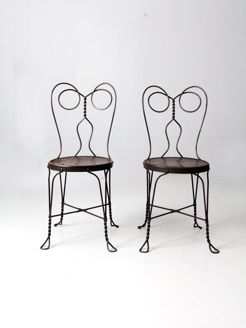 Vintage Pair of Antique Ice Cream Parlor Chairs with Twisted Metal Design: Vintage Pair of Antique Ice Cream Parlor Chairs with Twisted Metal Design This exquisite pair of early 20th century antique ice cream parlor chairs showcases a charming black metal bistro design, feat