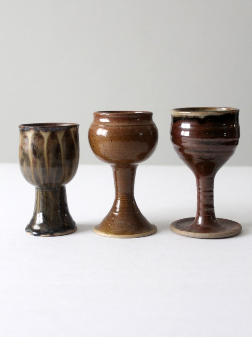 Handmade Vintage Pottery Chalice Set of 3 with Rich Brown Glazes: Handmade Vintage Pottery Chalice Set of 3 with Rich Brown Glazes Enhance your table setting with this exquisite set of three vintage studio pottery chalices. Each piece is uniquely crafted by differen
