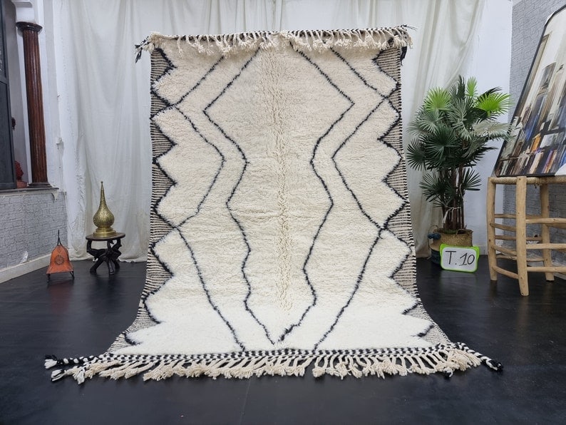 Authentic Moroccan Berber Wool Rug 3.28 x 6.56 Feet: Authentic Moroccan Berber Wool Rug 3.28 x 6.56 Feet This exquisite soft white handmade Moroccan Berber wool rug showcases a striking black assorted pattern and an engraved geometric frame. Crafted by 