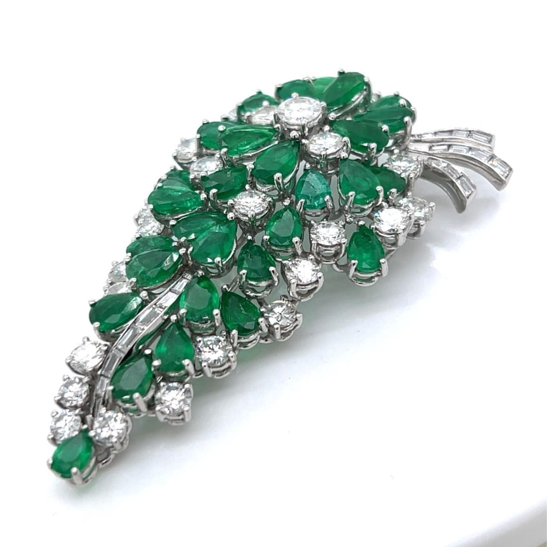 1950s Platinum Brooch with Colombian Emeralds and Diamonds: 1950s Platinum Brooch with Colombian Emeralds and Diamonds This exquisite 1950's Platinum brooch showcases a stunning arrangement of Colombian emeralds and diamonds. The piece weighs 24.6 grams and fe