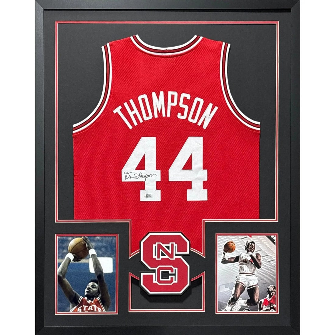 Framed N.C. State Red Jersey Signed by David Thompson Beckett Authenticated: Framed N.C. State Red Jersey Signed by David Thompson Beckett Authenticated This is a framed red jersey autographed by David Thompson, featuring the N.C. State logo. The signature is authenticated by 