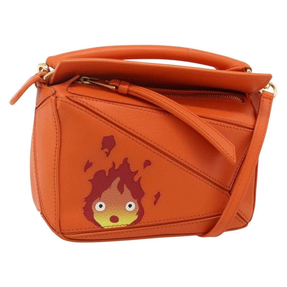 LOEWE Ghibli Calcifer orange leather mini 2way bag with strap: LOEWE Ghibli Calcifer orange leather mini 2way bag with strap This LOEWE x Ghibli Howl's Calcifer Puzzle Mini handbag features a vibrant orange and gold leather exterior. Designed as a 2-way bag, it c