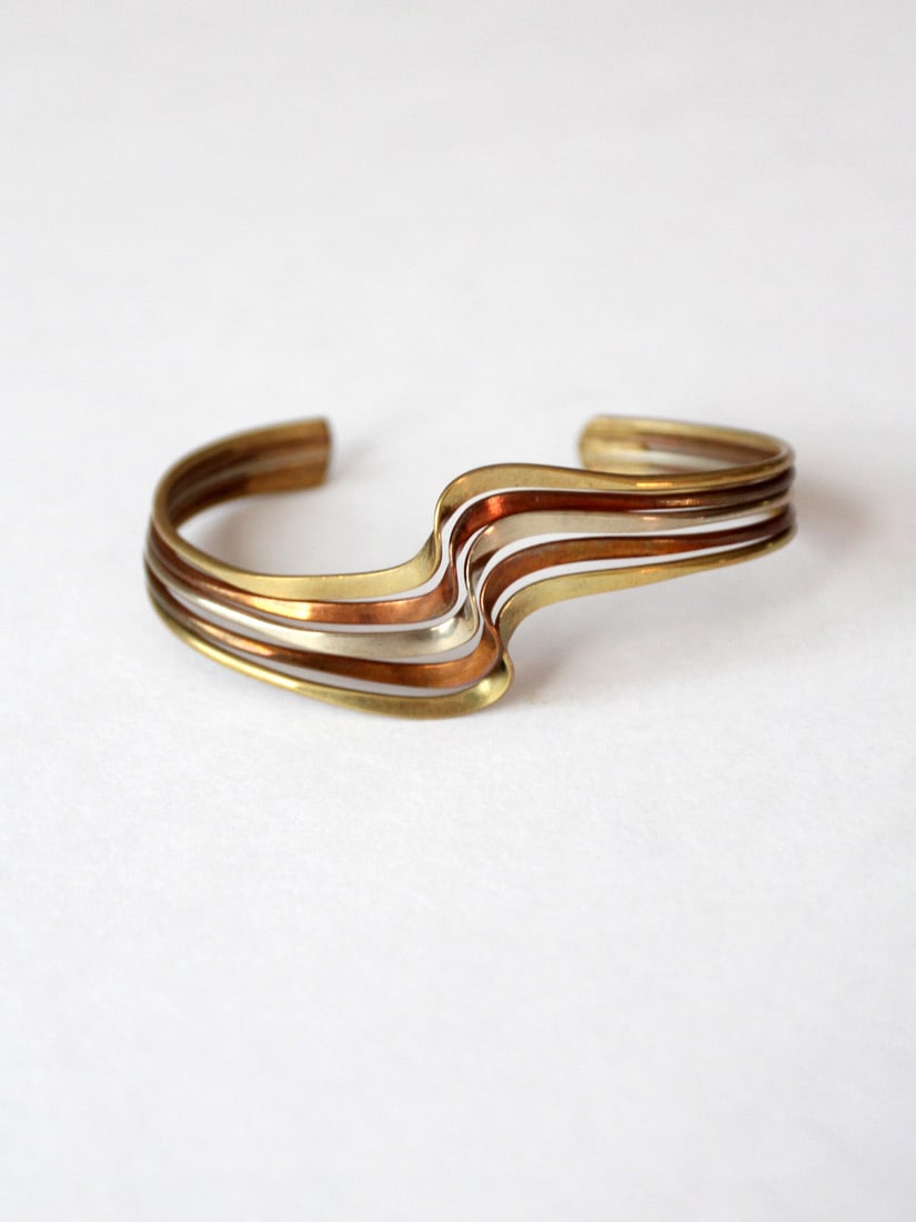 Vintage Brass Copper Silver Mixed Metal Cuff Bracelet: Vintage Brass Copper Silver Mixed Metal Cuff Bracelet This vintage cuff bracelet is a stunning piece crafted from a mix of brass, copper, and silver. The slender design showcases elegant waves of bras
