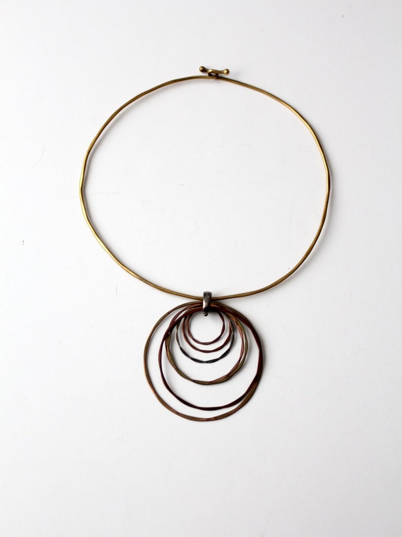 1970s Vintage Brass Collar Necklace with Mixed Metal Pendant: 1970s Vintage Brass Collar Necklace with Mixed Metal Pendant Discover a stunning piece from the 1970s with this vintage brass collar necklace featuring a striking mixed metal pendant. The slender bras