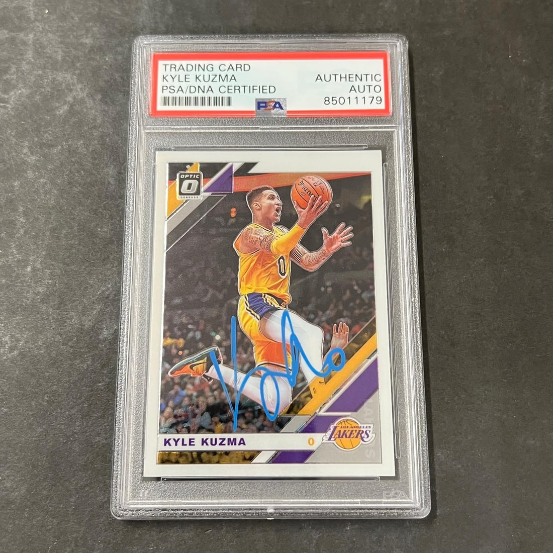 2019-20 Donruss Optic Kyle Kuzma Signed Card AUTO PSA Authenticated: 2019-20 Donruss Optic Kyle Kuzma Signed Card AUTO PSA Authenticated This is a 2019-20 Donruss Optic Basketball #80 card featuring the signature of Kyle Kuzma. The autograph has been authenticated by P