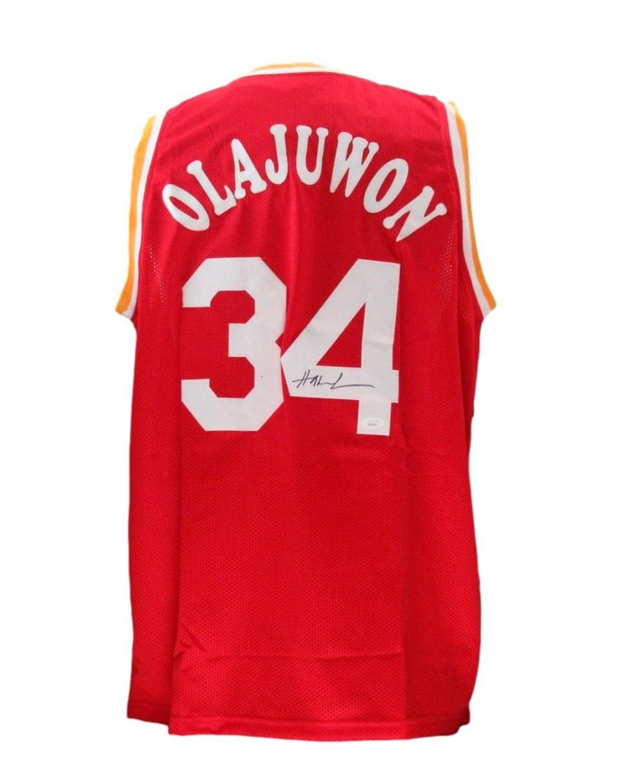 Autographed Red Custom Basketball Jersey Hakeem Olajuwon JSA Authenticated: Autographed Red Custom Basketball Jersey Hakeem Olajuwon JSA Authenticated This is a red custom basketball jersey, size XL, signed by Hakeem Olajuwon of the Houston Rockets. The autograph has been aut